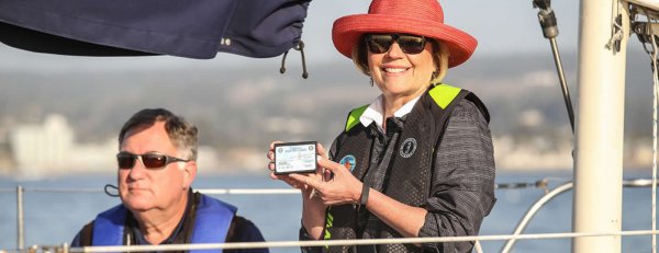 Older Woman Smiling with CA Boater Safety Card while her husband looks on.